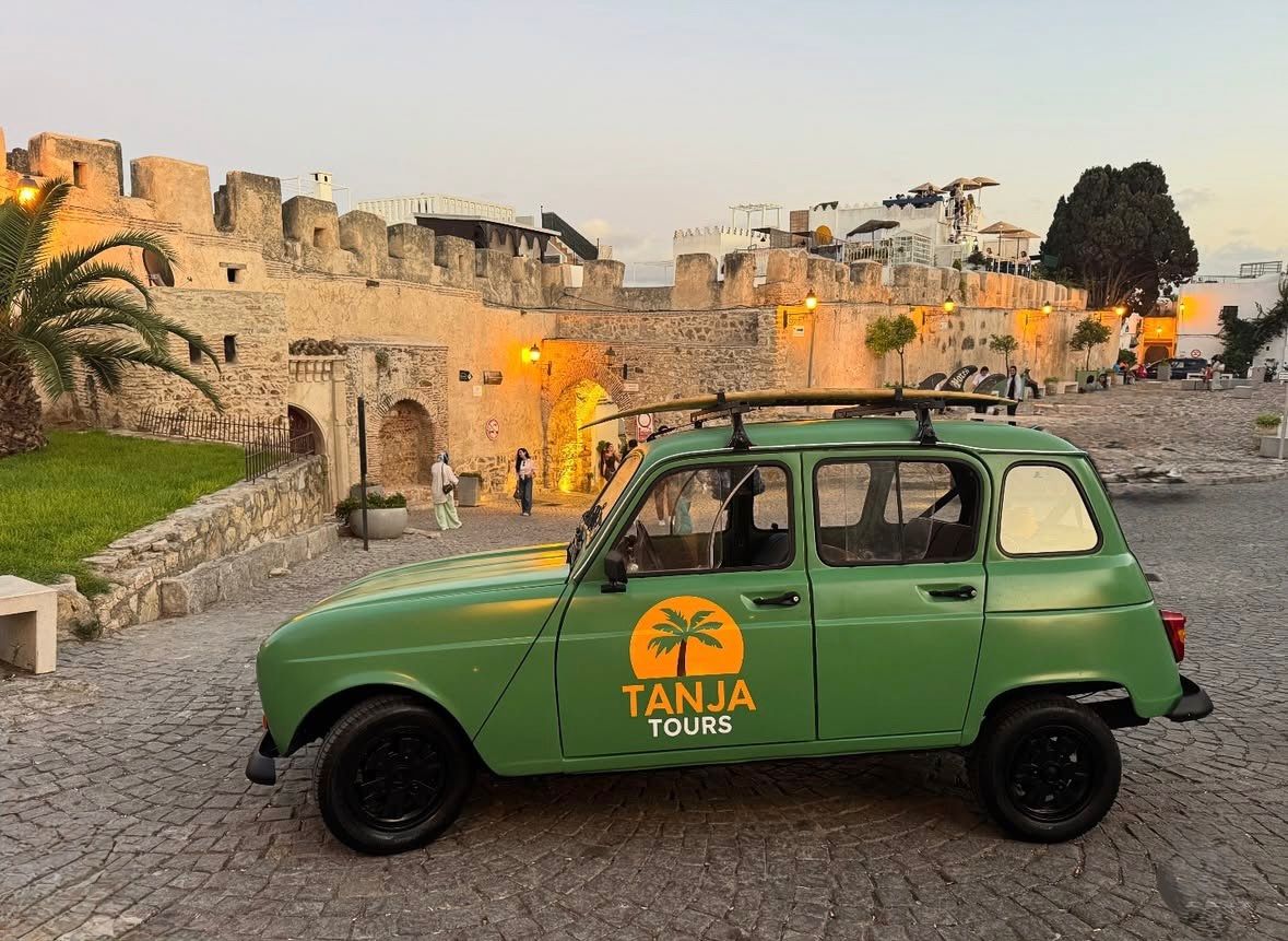 R4 avec planche de surf sur le toit devant les remparts d'Asilah au coucher du soleil